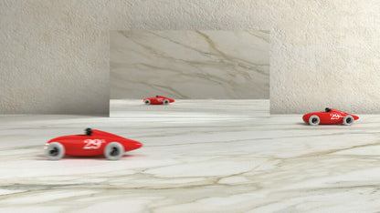 Red toy race cars on a marble surface with a mirrored background, showcasing unique veined patterns.
