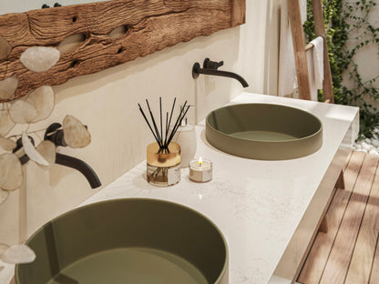 Modern bathroom design featuring green basins, decorative candles, and stylish fixtures on a sleek marble countertop.