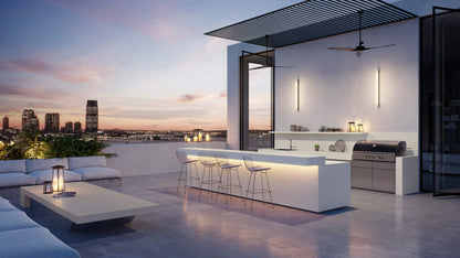 Modern outdoor kitchen with sleek design, city view, and elegant lighting at sunset.
