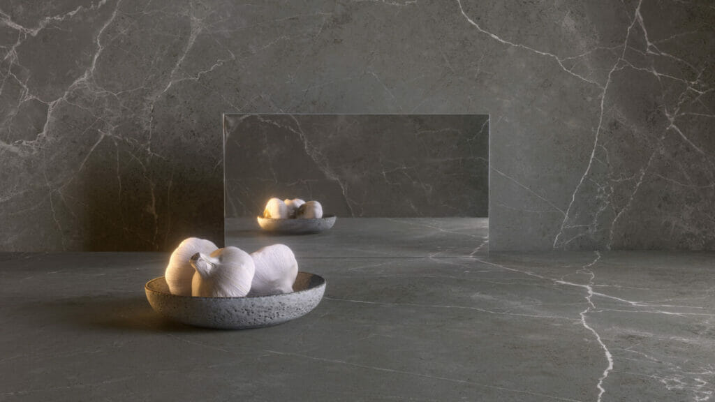 Honed dark grey surface with warm brown accents, showcasing a bowl of towels reflecting in a sleek mirror.