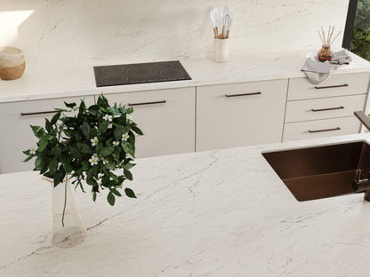 Modern kitchen with white marble countertop, sleek cabinets, and a vase of greenery for a stylish home decor.