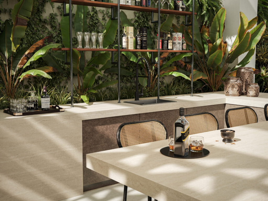 Stylish kitchen features a stone table, greenery backdrop, and modern bar with drinks and decor.