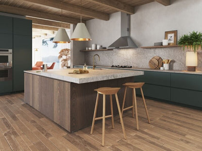 Modern kitchen featuring a spacious island, wooden flooring, green cabinetry, and stylish pendant lighting.