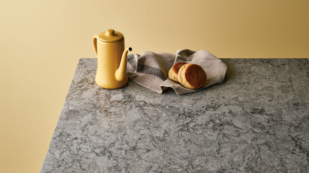 6313 Turbine Grey granite countertop with coffee pot and bread on a textured surface.