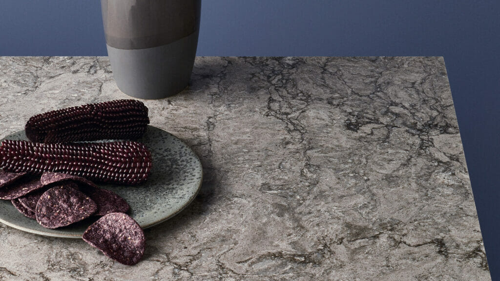 6313 Turbine Grey granite surface with dark and light veins, featuring snacks on a plate and a vase