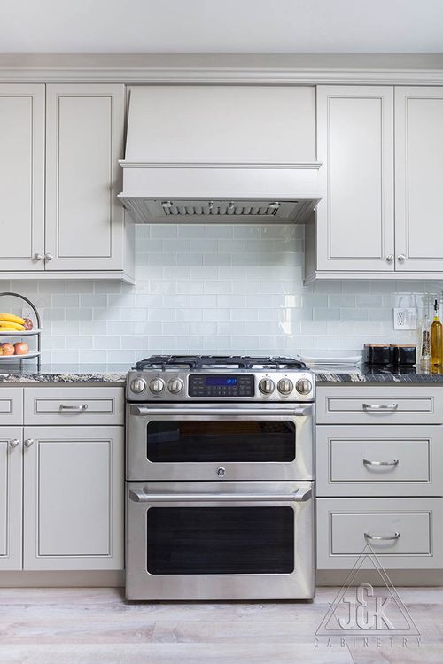 Modern kitchen featuring J&K's greige cabinets and stainless steel appliances, showcasing solid wood construction.