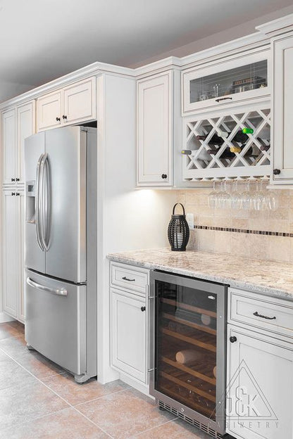 Modern kitchen featuring J&K's Pearl Glazed cabinets, stainless steel fridge, and wine cooler with granite countertops.