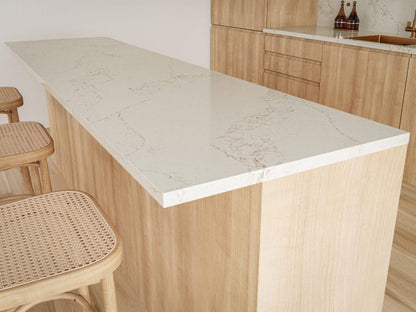 Modern kitchen island with white marble countertop and light wooden cabinetry featuring rattan bar stools.