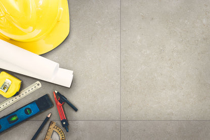 Livingstyle Pearl 18x36 Matte pavers with construction tools and a yellow hard hat on a gray surface.